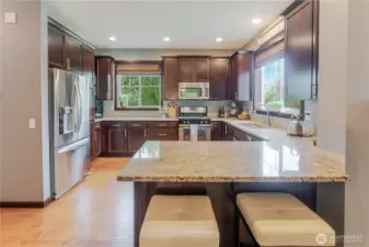 Well-equipped kitchen with rich cabinetry, granite surfaces, and stainless-steel appliances, featuring a central peninsula with casual seating for easy mornings or impromptu gatherings