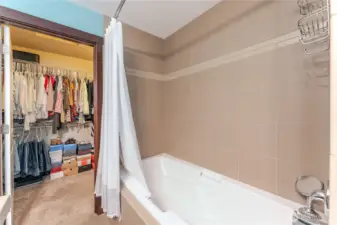 View from the primary bath into the expansive walk-in closet—offering generous storage, thoughtful organization, and direct access to a spacious attic for even more versatility