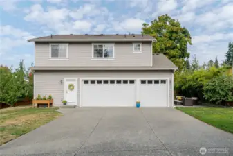 Another view of the three-car garage, framed by mature apricot trees on the left, offering generous parking, alley access and room to make this garden your own