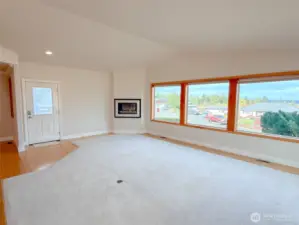 Living room portion of great room with three large windows bringing in the natural light and views.