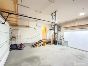 Opposite side view of the attached garage, showing additional storage shelving and entry to the laundry room.