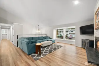 The spacious great room showcases soaring vaulted ceilings and is bathed in natural light from huge picture windows (new in 2024).  Elegant LVP flooring enhances the brightness throughout the main level.