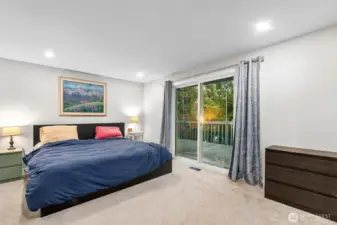The expansive primary suite accommodates a king bed with ease and boasts a spa-inspired tile bath, a spacious walk-in closet, and direct access to the upper deck overlooking tranquil trees.