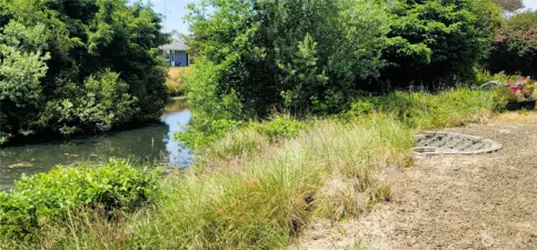 Nestled beside a serene stretch of canal, this lush coastal sanctuary offers natural beauty just steps from your door. The low-maintenance landscaping frames a peaceful waterside view, while a private firepit area invites evenings spent under the stars in pure Surfside tranquility.