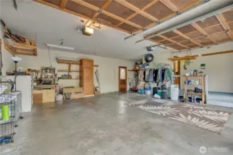 Oversized garage with room for storage and a separate door that leads to a deck.