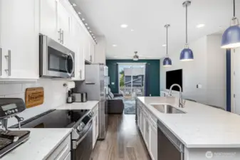 Light, bright, and open kitchen showcases quartz countertops, stainless steel appliances, a spacious island with sink, and seating—perfect for cooking and gathering.