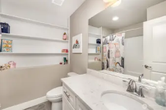 Downstairs full bathroom also boasts built-in shelving, quartz countertops, and a dedicated outlet for smart toilets or bidets.