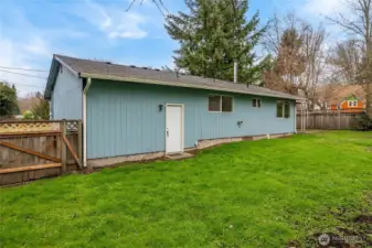 Back of home with man door from garage space.