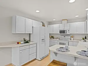 The spacious kitchen is flooded with natural light from the windows and sliding glass door to the upper deck.