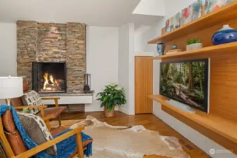 Private main floor office with a stacked stone fireplace and custom entertainment shelf.