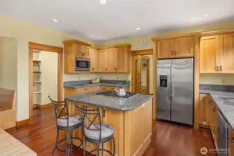 Another view of the kitchen. Oversized walk in pantry doubles as a small home office with built in desk. Door to the left of the refridgerator heads to the half bath, garage, exterior door and second stairwell to large ensuite bonus room.