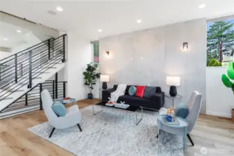 Generously sized second level living room with tall ceilings, dramatic center staircase, large format porcelain tile accent wall, Oak plank flooring, territorial views, air conditioning and great light.