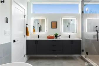 Primary en-suite bathroom with dual sinks, back it vanity mirrors, storage and great natural light.