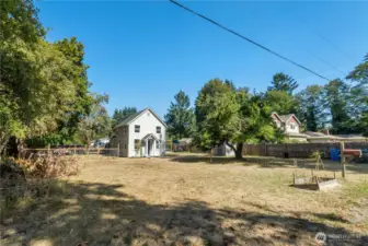 Spacious front lot framed by mature trees, offering a glimpse of the home’s orchard roots and plenty of space for outdoor living or future projects