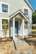 Inviting entryway with fresh stone pathway and charming covered porch, a thoughtful touch that blends history with everyday convenience.
