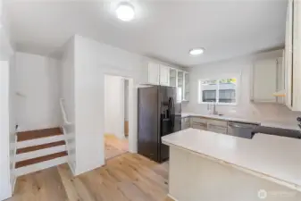 This light-filled kitchen highlights a practical layout with plenty of counter space and cabinetry, blending vintage character with everyday convenience. Large windows brighten the space, while the open flow connects easily to the rest of this historic 1910 home. Lots of cabinetry in this kitchen.