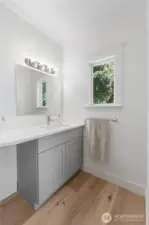 Crisp and refreshed, this bathroom combines clean lines with natural light. The modern vanity and quartz-style countertop provide everyday functionality, while the window frames views of the leafy surroundings, tying the space back to the home’s original charm.