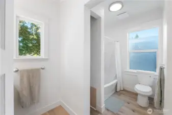 Bright and functional, this full bathroom offers a blend of historic simplicity and modern updates. A window above the tub brings in natural light, while crisp finishes and thoughtful design ensure comfort and convenience.