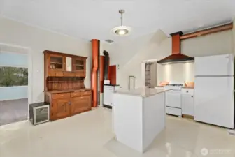 The updated kitchen showcases a marble slab island, resilient epoxy floors, copper accents, and custom lighting.