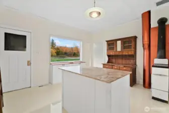 Providing both functionality, beauty and flow, the kitchen offers garage access, ample storge options, classic early 1900s features, and picturesque views from the over-sized window.