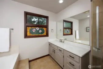 Primary Spa-like bathroom w/quartz countertops/tile floors & refinished soaking tub.
