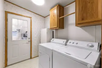 Laundry room with upper cabinetry and convenient access near the back entry