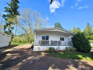 Wide exterior view showing the home’s setting, parking, and surrounding landscape