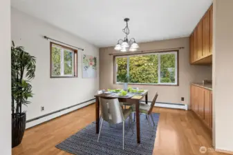 Another view of the dining room with windows looking out toward the patio and terraced landscaping. The kitchen is to the right.