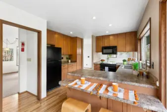 The kitchen offers ample storage & counterspace with a sweet breakfast bar, window looks out to the back side of the home. The pass-through on the left leads to the living room and the stairway to the bedrooms. There is a sliding glass door on the right that leads you to a patio, terraced garden beds and the back yard. The back yard is partially fenced. From the breakfast nook, there are also stairs that lead down to the main level.