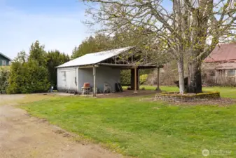 The tool shed with an enclosed area as well as a covered area for firewood storage. New metal roof.