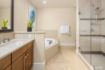 Spa-inspired primary bath featuring a deep soaking tub, glass-enclosed shower, dual vanities, and timeless tile finishes.