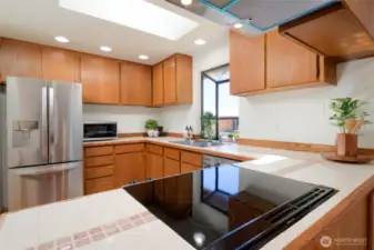 The light-filled kitchen hosts Stainless steel appliances, glass cooktop and garden window.