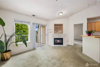 Living Room with Fireplace: Cozy gas fireplace anchors the living space, with vaulted ceilings and access to the private deck overlooking a lush greenbelt.