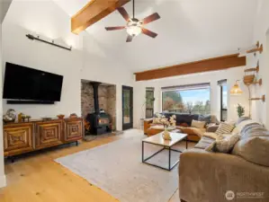 The family room has a cosy wood stove and tall ceilings with solid beam details.