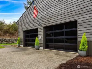 Large oversized garage with designer doors, multiple refrigerators and storage shelving.