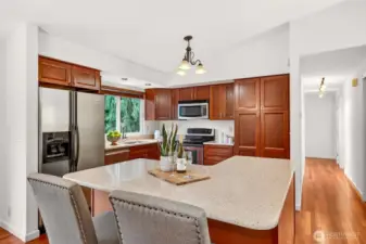 This kitchen delivers great storage and a clean, classic look with wood cabinetry, stainless microwave and range, and wide counters that keep everything within reach. The oversized island offers a true gathering space, ideal for meal prep, appetizers, and casual dining without losing the open connection to the rest of the home. Hardwood flooring ties it all together with warmth and durability.