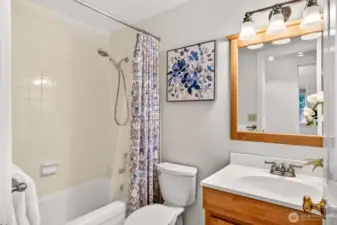 This full bath is clean and functional, featuring a tile tub and shower surround, a bright vanity, and a wood trimmed mirror with a multi light fixture overhead. It’s an easy, comfortable space for daily routines, with finishes that feel straightforward and timeless. The layout keeps everything simple, efficient, and ready for everyday use.