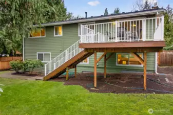 From the yard, you can see how the raised deck becomes a true centerpiece, offering both privacy and a great vantage point over the outdoor space. The green siding and crisp trim present a classic Northwest exterior, and the lawn provides room to relax, garden, or set up outdoor gatherings. It is a backyard that feels open yet sheltered, with mature trees adding the right amount of seclusion.