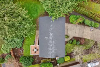 A top down view highlights the home’s footprint, the deck placement, and the surrounding greenery. You can also see the driveway and hardscape, giving a clear sense of the lot’s layout and outdoor flow.