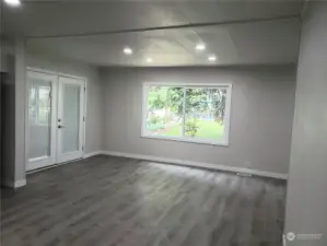 Huge Extra Living Room Area of the Double Wide Home with All New Painted Walls, Trim, Vinyl Plank Flooring and Double Door Entry to the Front Covered Front Porch.