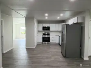 Another View of the Huge Open Kitchen with All New White Cabinets, Counter Tops, Double Sink, Faucet, Stainless Appliances and Vinyl Plank Flooring.