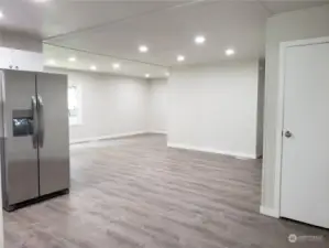 Different View of the Huge Open Kitchen with All New White Cabinets, Counter Tops, Double Sink, Faucet, Stainless Appliances and Vinyl Plank Flooring Showing The Extra Living Room Area off the Covered Front Porch.