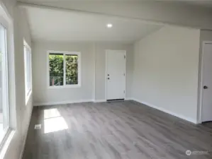 Huge Living Room Area with All New Painted Walls, Cathedral Ceiling, Trim, New Vinyl Windows, Vinyl Plank Flooring Looking at the Front Door Entry to the Front Covered Front Porch.