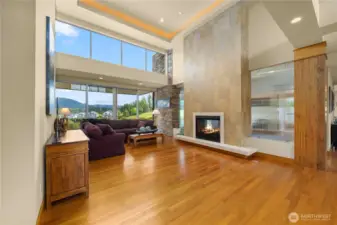 This striking living room is a masterpiece of design, featuring a floor-to-ceiling slate surround that frames the sleek gas fireplace, creating a bold yet inviting focal point. Towing floor-to-ceiling windows capture the breathtaking panoramic views and bringing the beauty of the outdoors in.  Sophisticated and serene, it's the perfect place to relax, gather, and take in the stunning scenery.