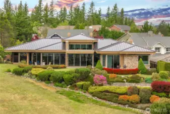 The rear of the house showcases a stunning wall of windows that flood the interior with natural light and frames panoramic views of the golf course and distant mountains. This large lot is adorned with mature, beautifully maintained landscaping and lush shrubs, creating a serene retreat that perfectly complements the scenic surroundings.