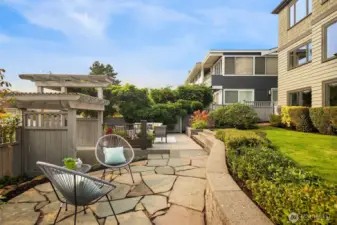 The covered patio off the lower level steps out to the grassy stretch on our right, and then down to two separate hang-out spaces.  Stairs in between step down to the detached garage and access to the quiet street below.