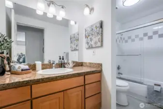 Bathroom with granite countertops and bathtub/shower.