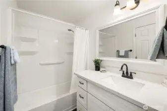 Adjoining full bathroom with quartz countertops.