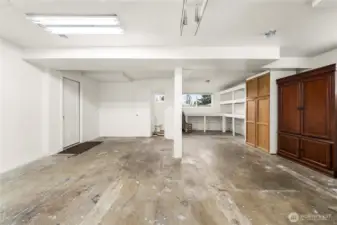 View of huge garage, with bathroom, workbench & storage.
