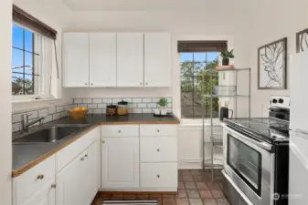 Updated corner kitchen with greenery and city views, bright updated cabinetry and ample storage and cooking space.